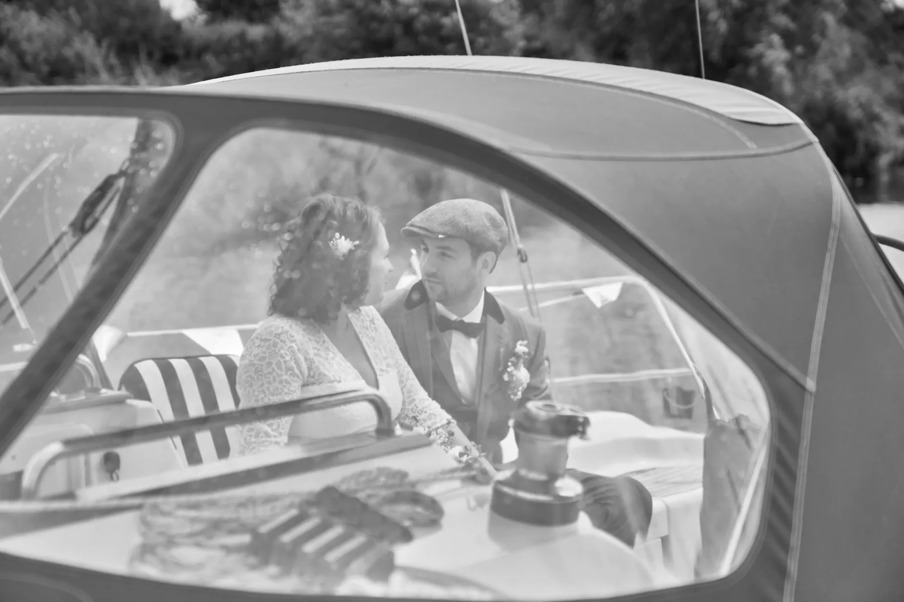 Bruidspaar in een klassieke trouwauto, in zwart-wit gefotografeerd